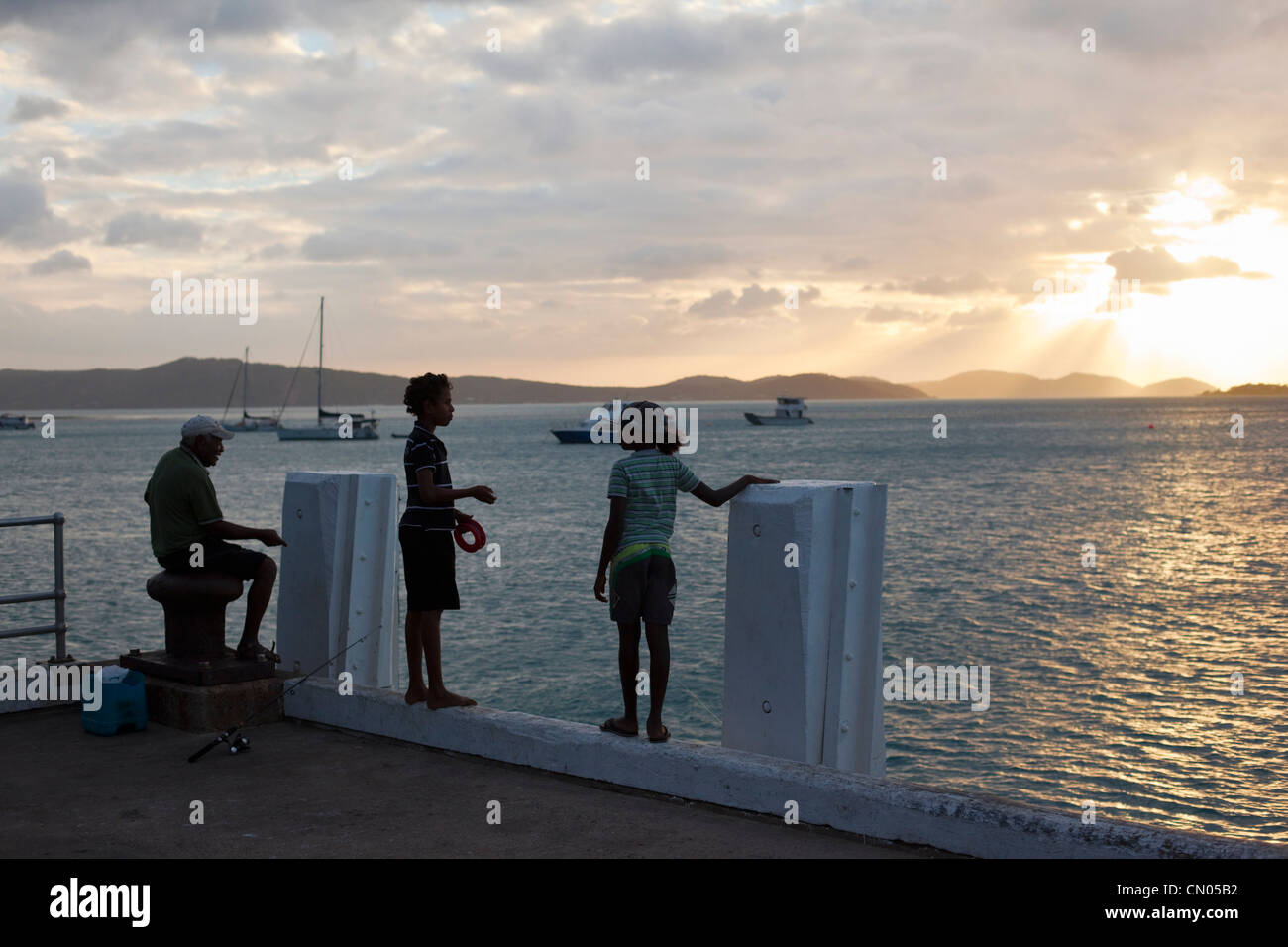 Children fishing off the jetty at sunset.  Horn Island, Torres Strait Islands, Queensland, Australia Stock Photo