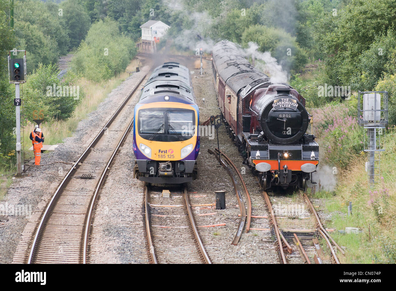 Steam locomotive pulling a passenger train on the main line and passing a diesel passenger train on the Pennine route Stock Photo