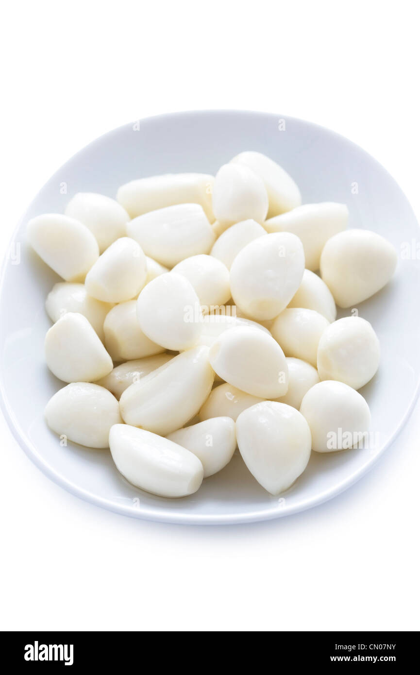 peeled pickled garlic cloves in a dish on a white background Stock Photo