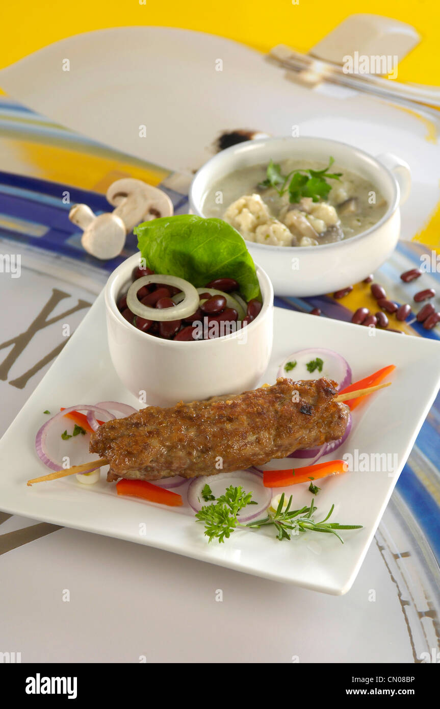 spicy meat rods with bean salad with onion Stock Photo