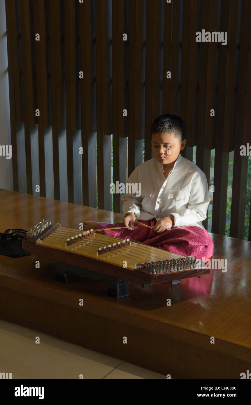 A young Thai boy plays a traditional khim instrument, Phuket, Thailand