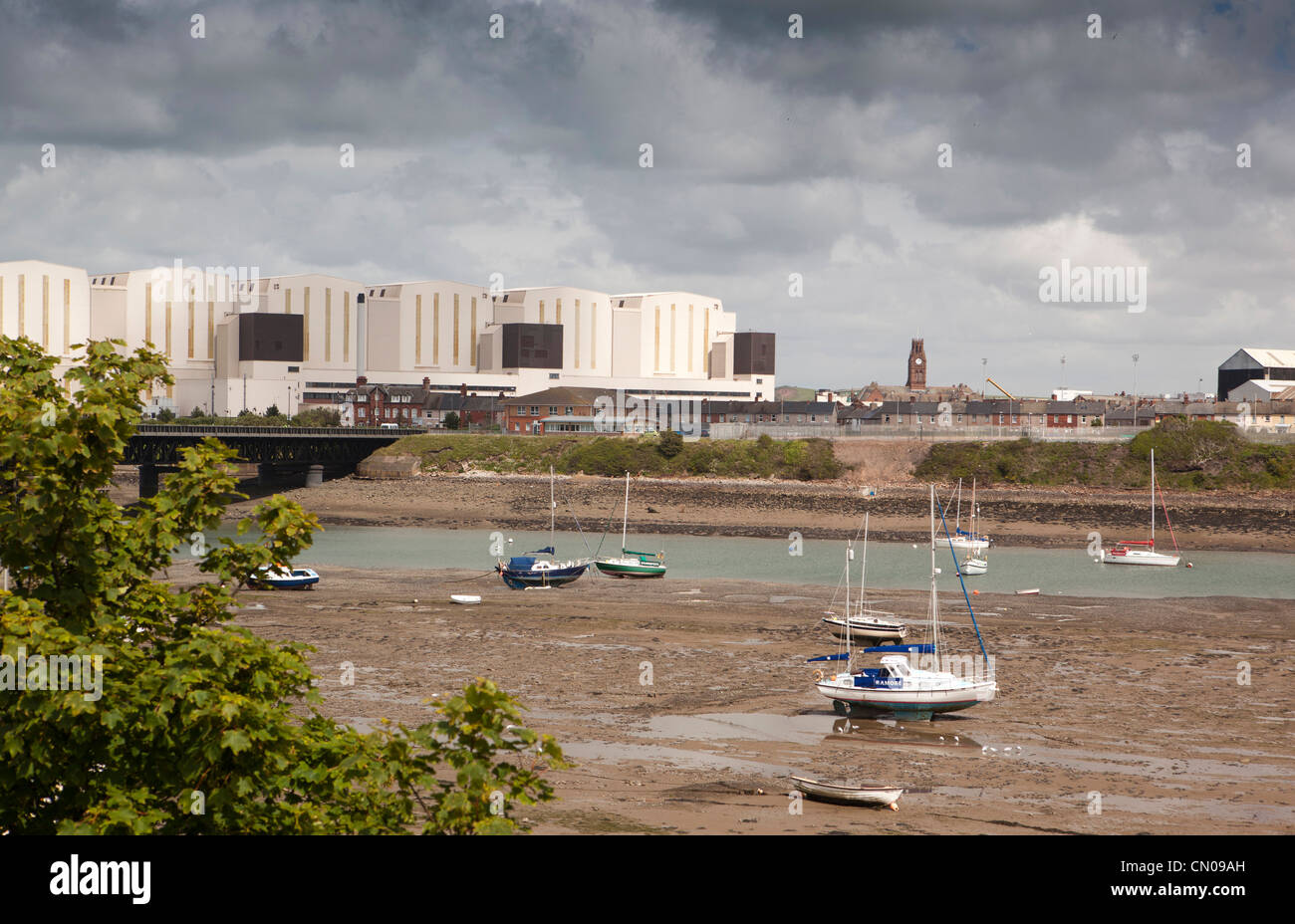 UK, Cumbria, Barrow in Furness, boats moored in Walney Channel at low tide in front of Bae systems shipbuilders Stock Photo