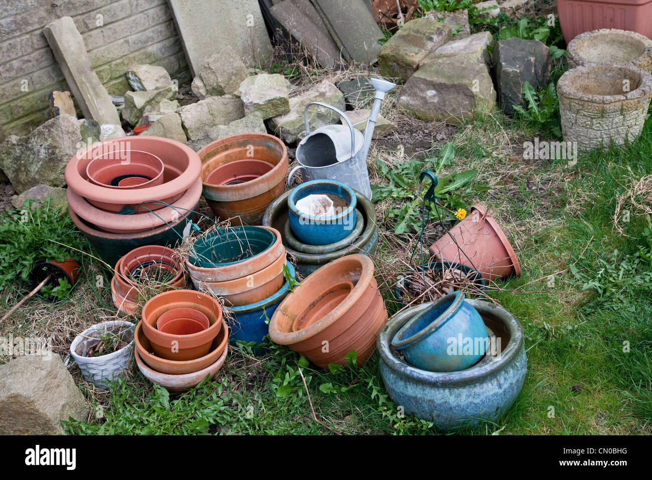 Assorted garden flower pots watering can and rocks in English garden