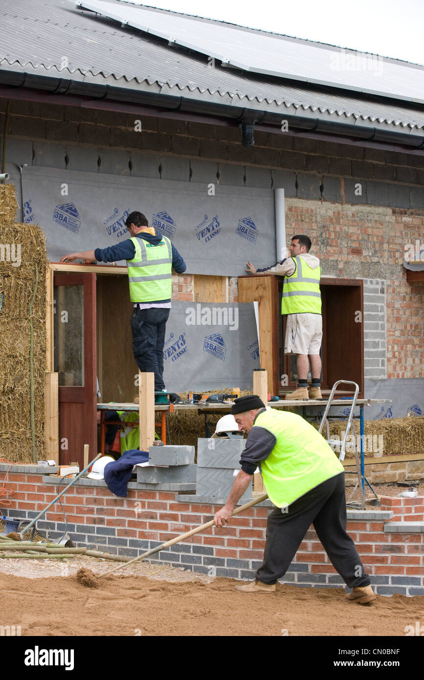 Builders using straw for insulation on a new Eco-friendly building Stock Photo