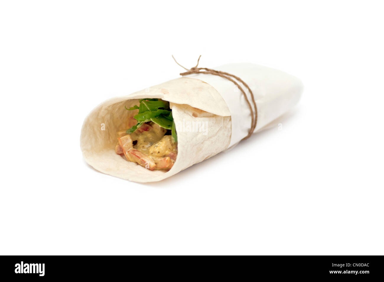 A wrap with meat, salad and tomatoes wrapped in a paper on a white background Stock Photo