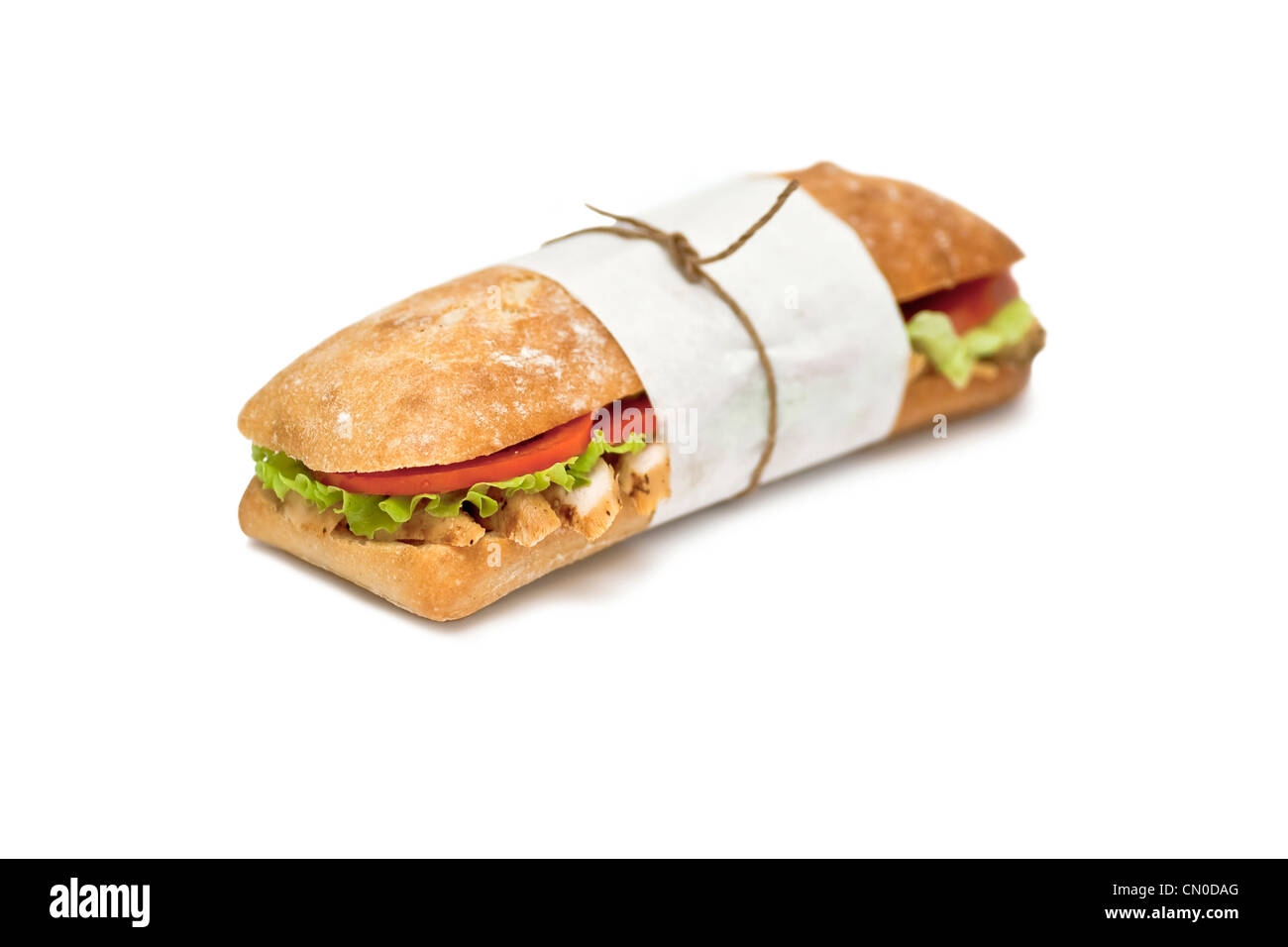 A sandwich with meat, salad and tomatoes wrapped in a paper on a white background Stock Photo