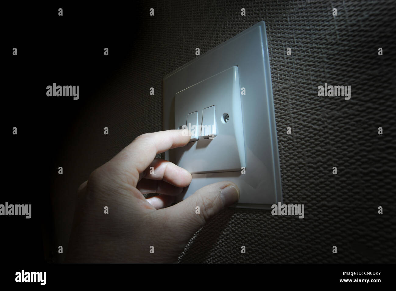 MANS HAND FINGER WITH DOMESTIC LIGHT SWITCH RE ELECTRICITY BILLS FUEL COSTS THE ENVIRONMENT ELECTRIC FOSSIL FUELS SWITCHING OFF Stock Photo