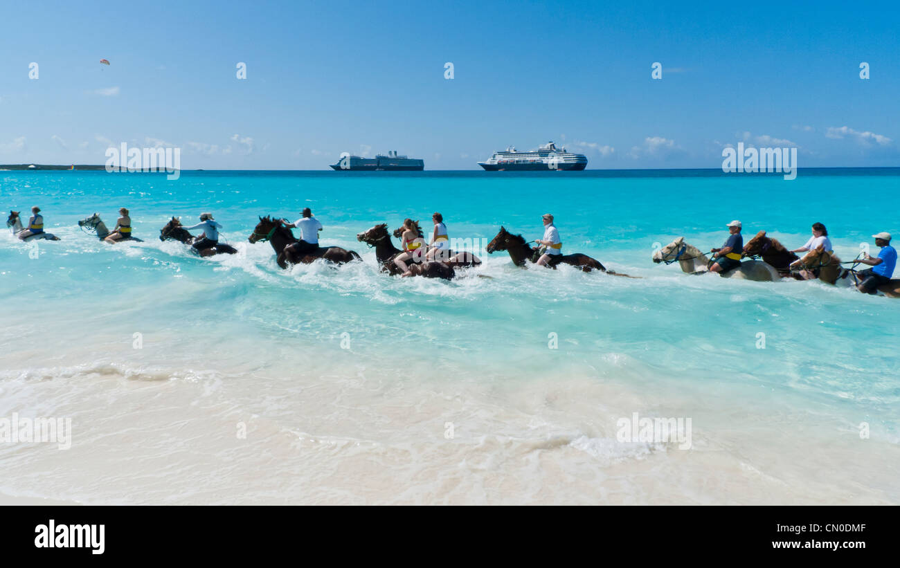 Cruise ship passengers ride horses through the surf at Half Moon Cay in