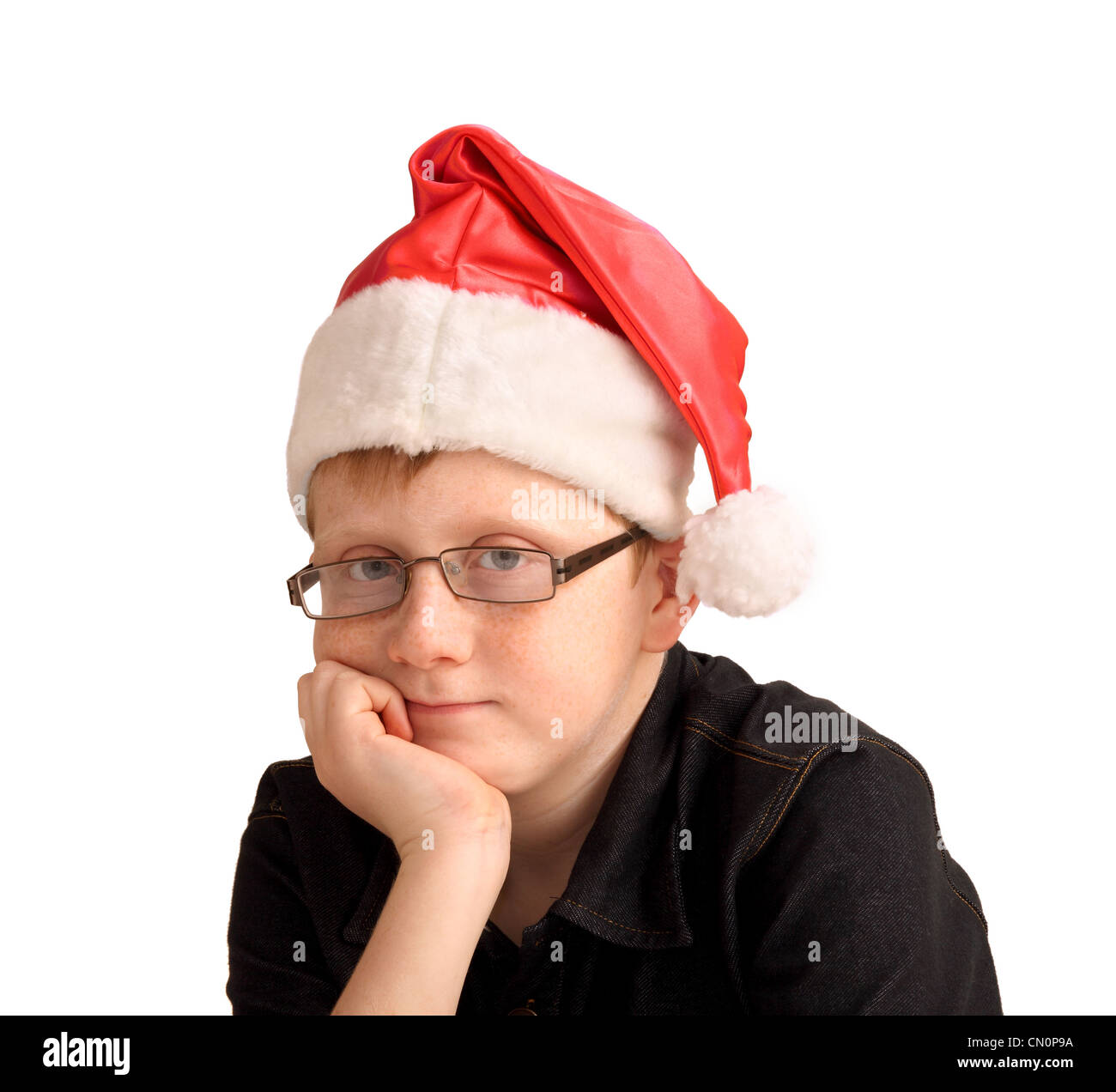 A 12 year old boy, with a slight smile, wearing a 'Santa' hat Stock