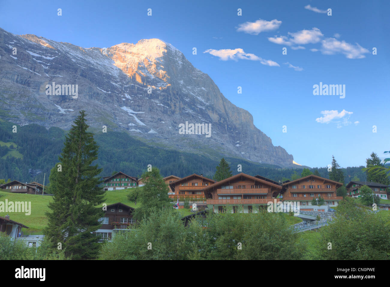 timber chalet huts with dewy meadow and mountain Eiger top glowing in