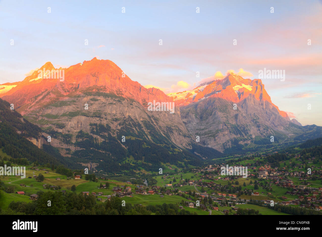 Alpenglow over alpine town Grindelwald in valley at sunset in front on mountain Eiger north face, Switzerland Stock Photo