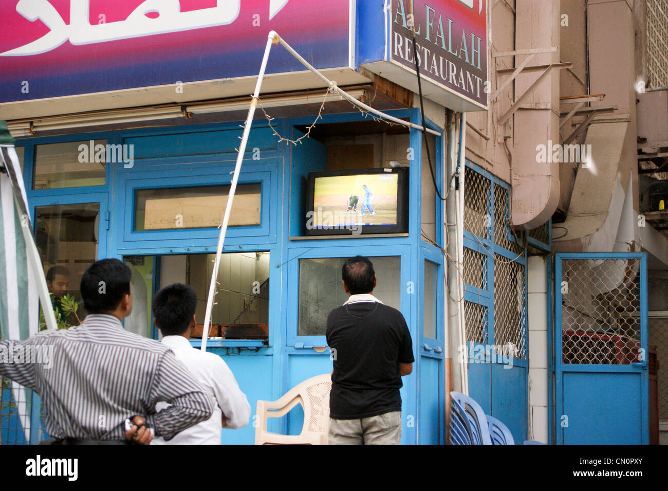 Men watching cricket on a television set on the street, Dubai, United Arab Emirates Stock Photo