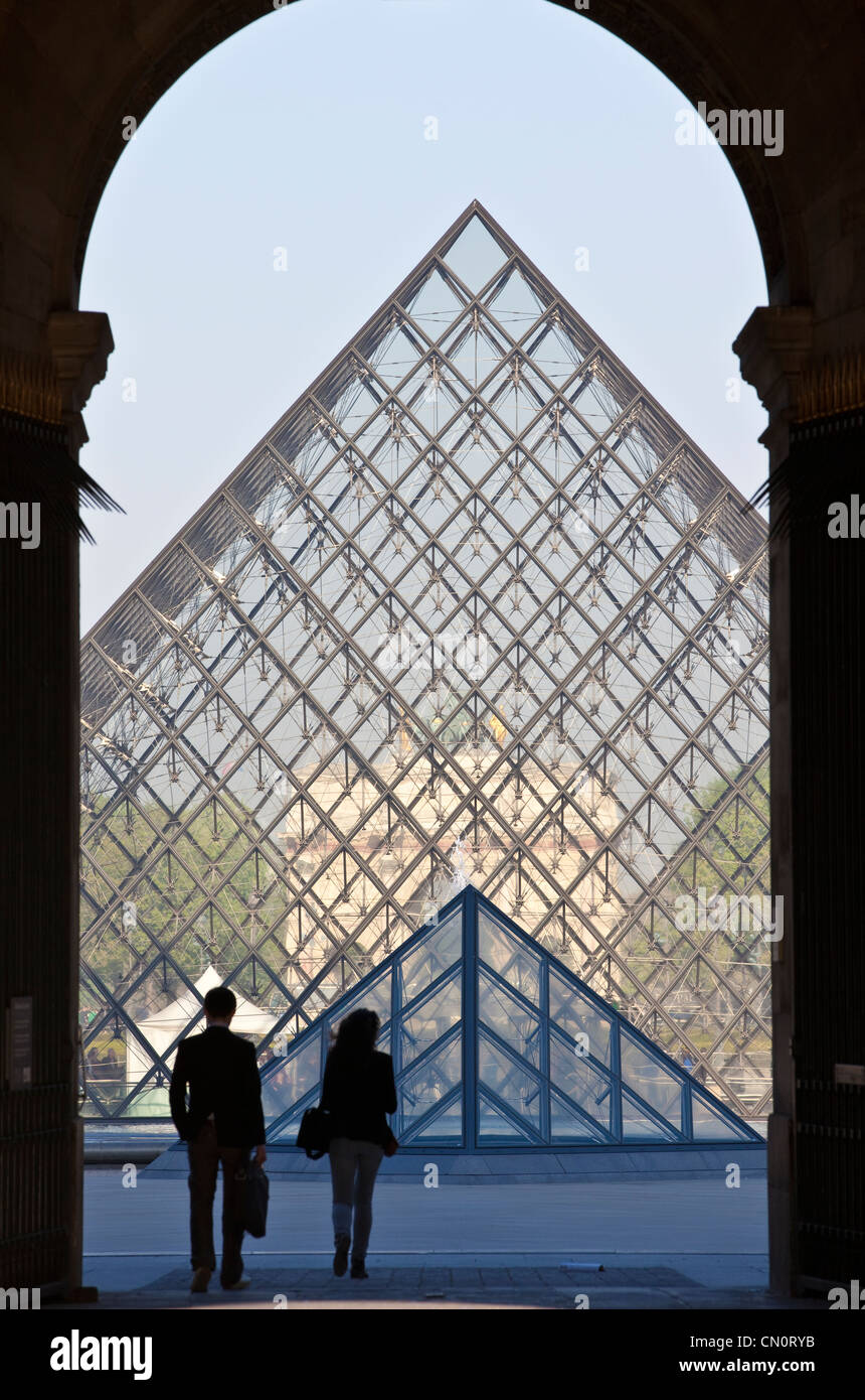 A couple walk towards the glass pyramid at Musée du Louvre, Paris, France. Stock Photo