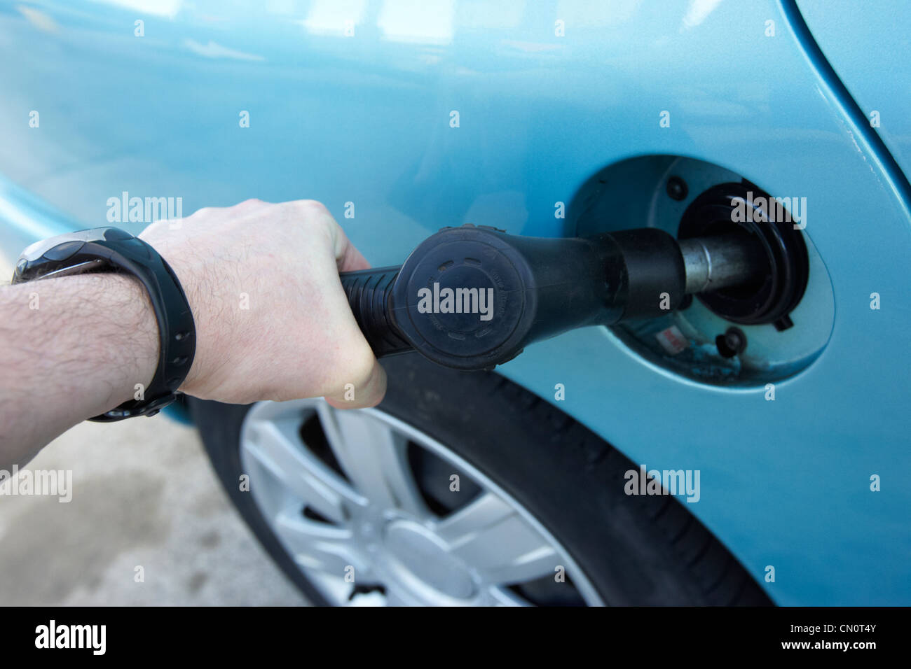 man filling up car with diesel fuel pump inserted into car fuel tank Belfast Northern Ireland UK Stock Photo