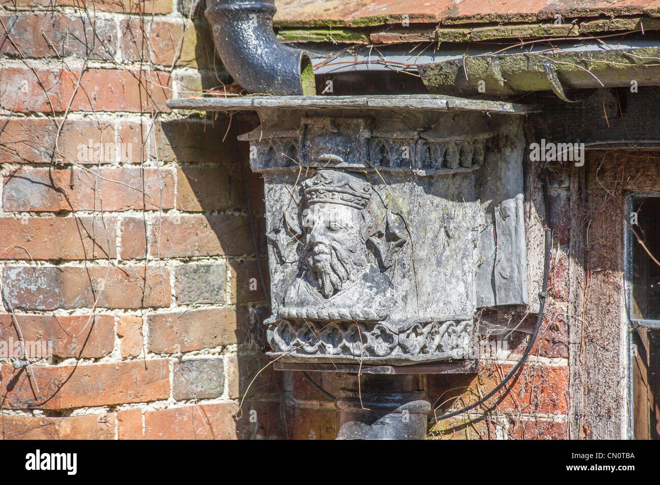 A lead hopper with a crowned head, forming part of an old guttering system with old brickwork Stock Photo