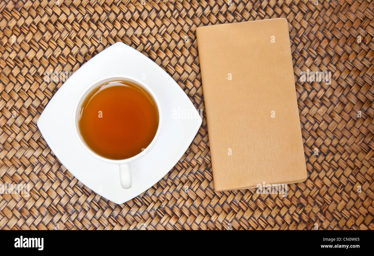 Tea and brown notebook on sedge background Stock Photo