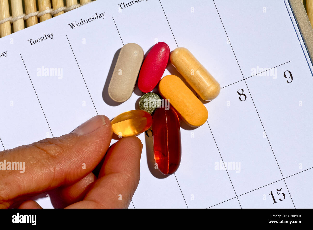 Vitamins and minerals on calendar with fingers reaching to pick one up Stock Photo