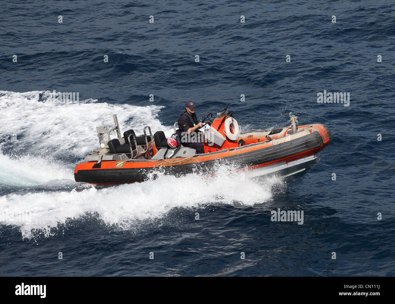 A Maltese coastguard steers a Zodiac inflatable at speed between the Mediterranean islands of Malta and Gozo Europe Stock Photo