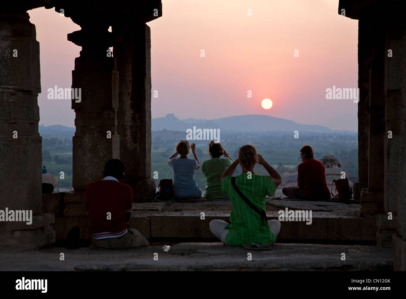 Tourists contemplating the sunset from a temple. Hemkutha Hill. Hampi. India Stock Photo