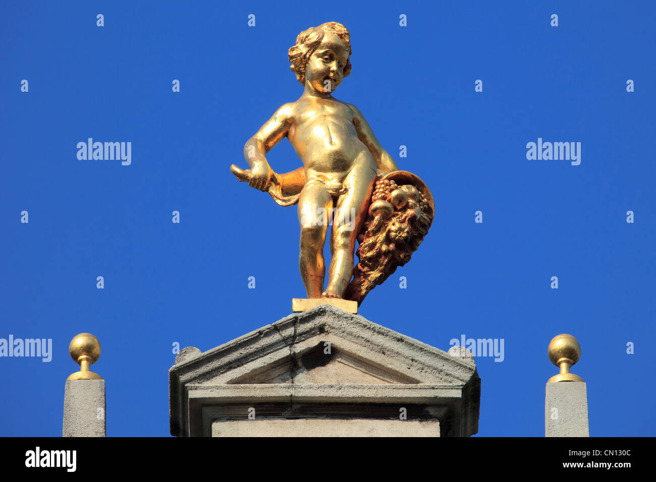 Golden statue of a naked boy holding the horn of plenty on top of