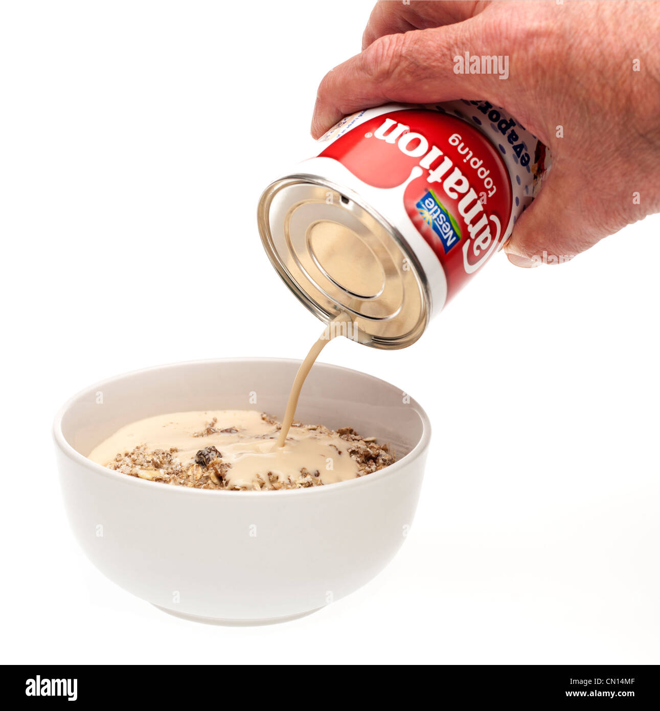 Tin of Carnation topping cream pouring onto a dish of muesli Stock Photo