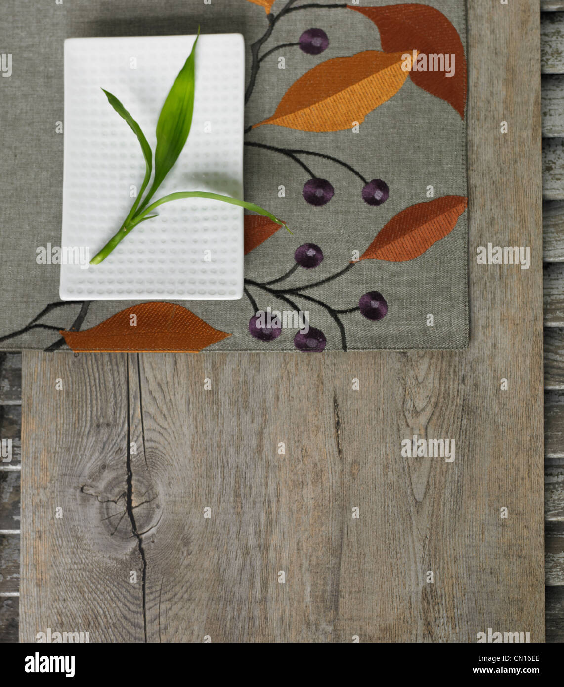 Small white plate on wooden surface with bamboo leaf Stock Photo