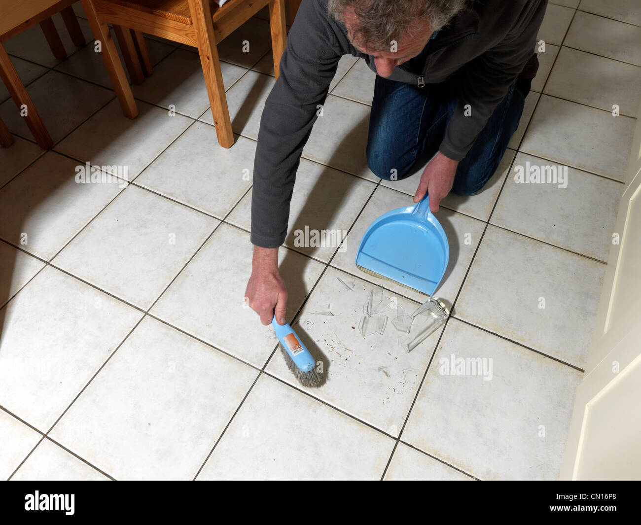 Man Cleaning Up Broken Glass Of The Floor Using Dustpan And Brush Stock
