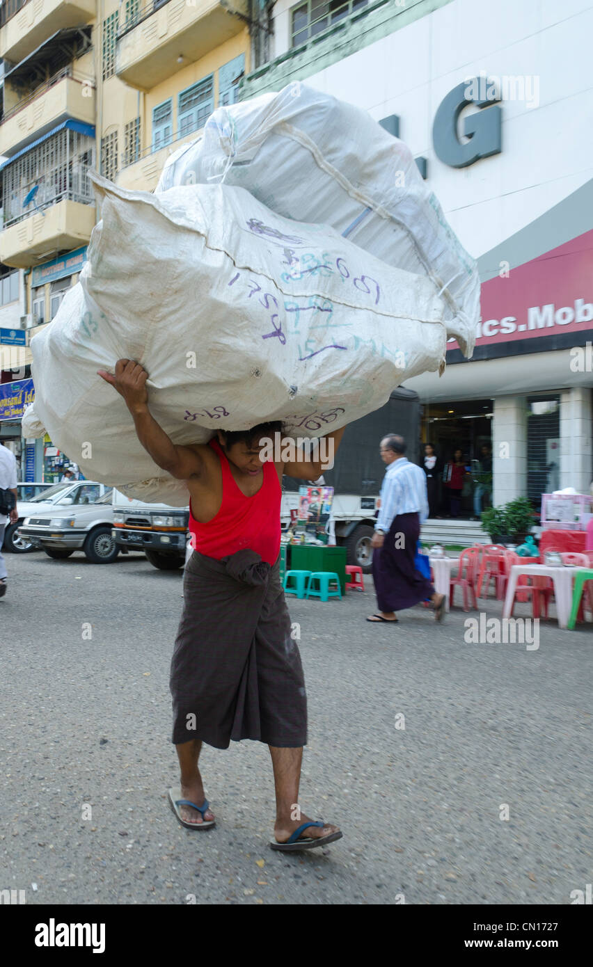 Porter carrying huge bag in the streets of Yangon. Myanmar Stock Photo