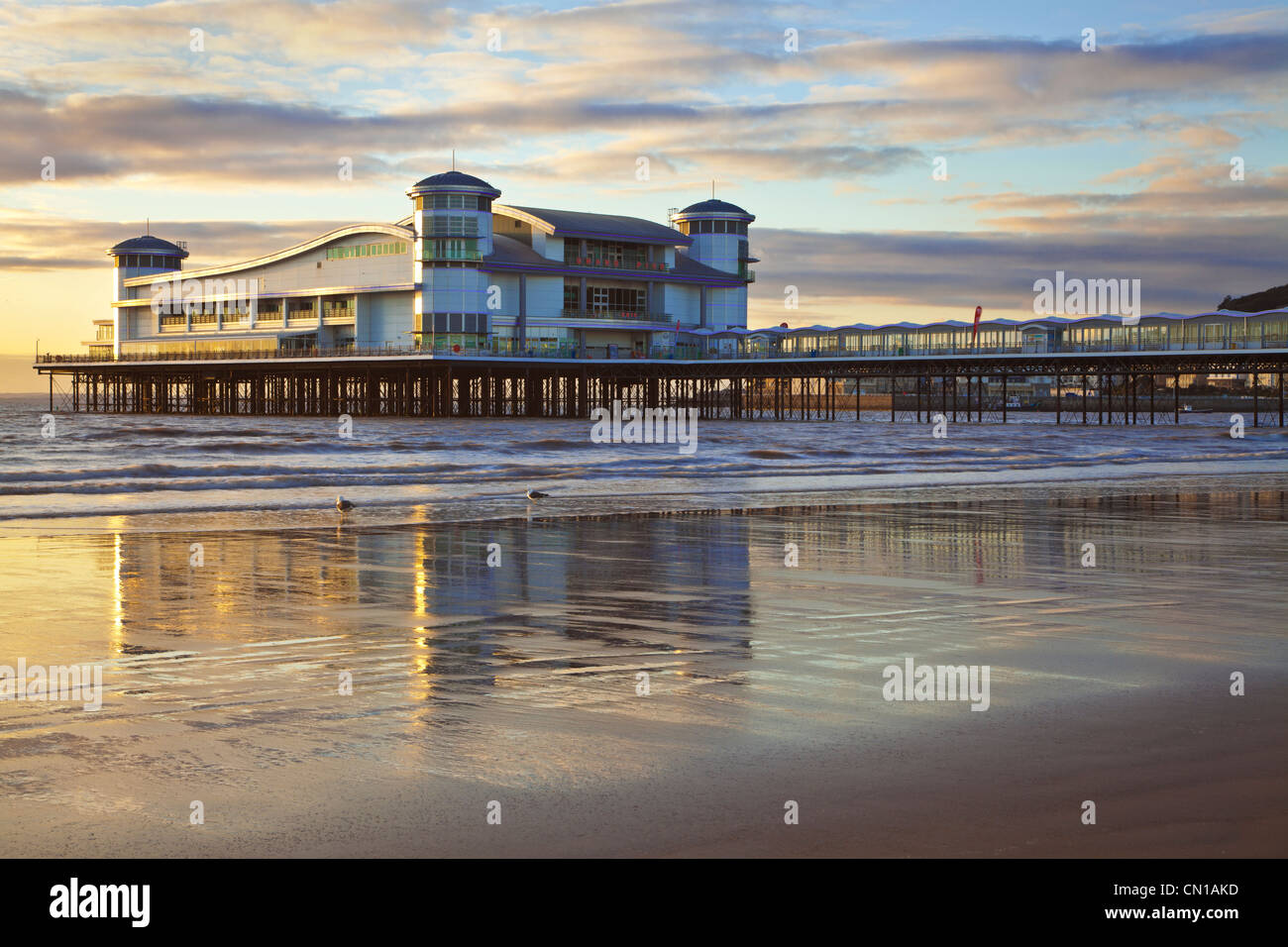 Golden evening light falls on the Grand Pier at Weston-Super-Mare, Somerset, England, UK reflected in the wet sand at high tide. Stock Photo