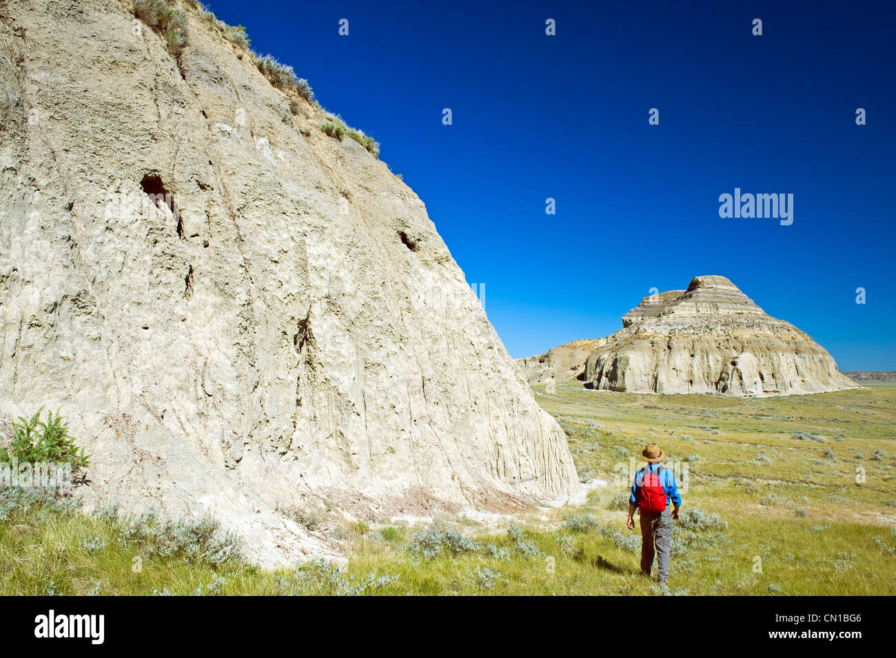 A hiker walks towards Castle Butte, Big Muddy Badlands, Saskatchewan Stock Photo