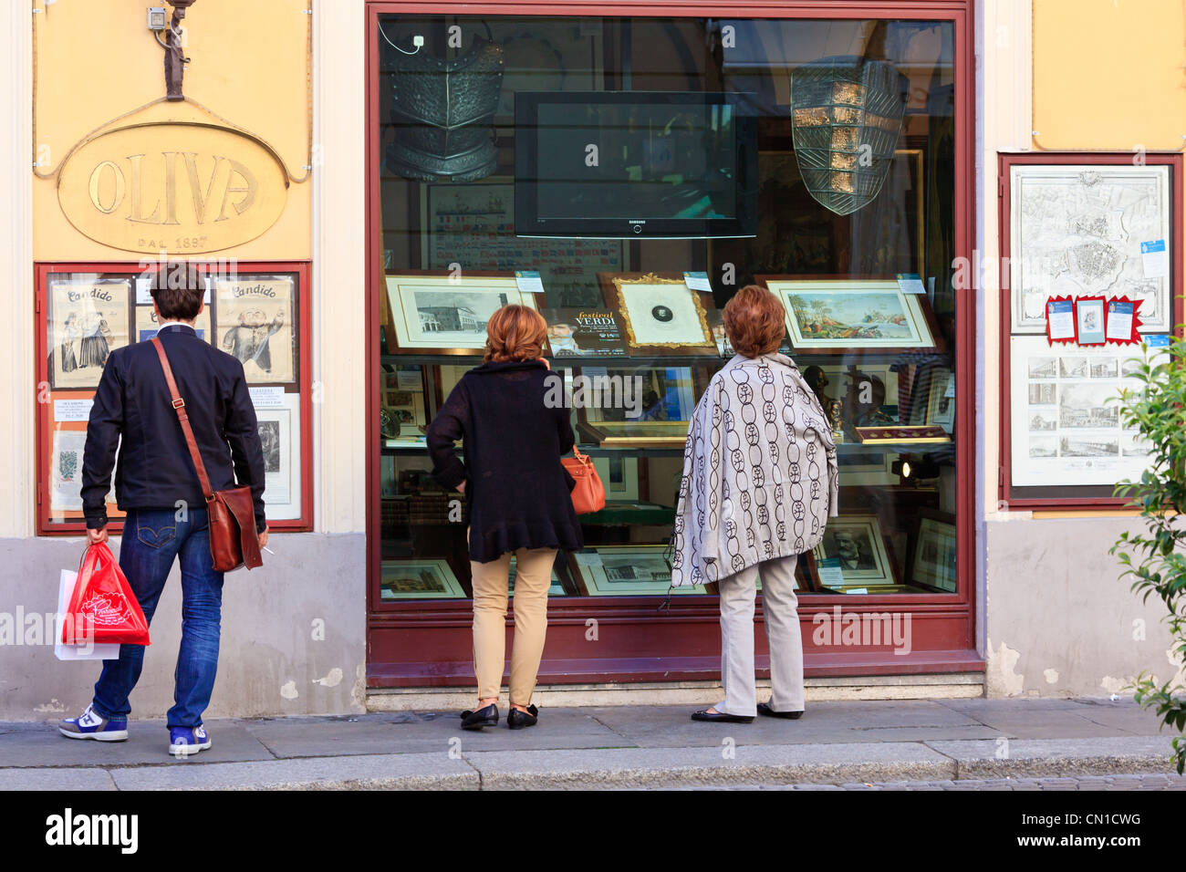 Bystanders looking on a Verdi exhibition in a picture framing shop in Parma, Emilia-Romagna, Italy Stock Photo