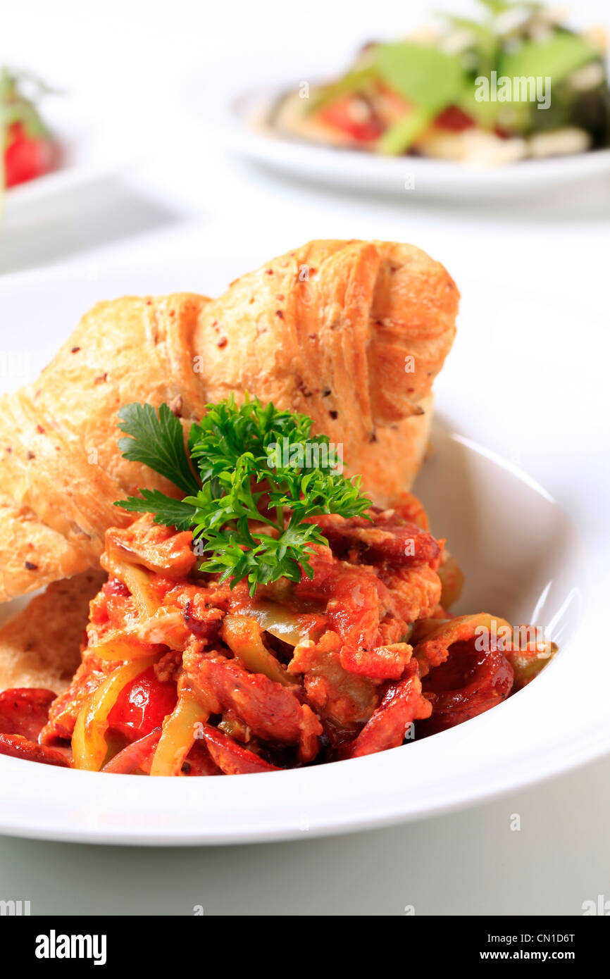 Vegetable stew with slices of sausage and croissant Stock Photo