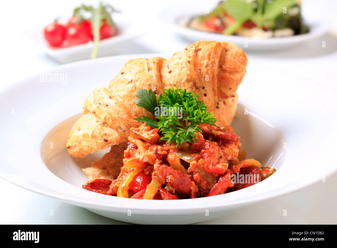 Vegetable stew with slices of sausage and bread roll Stock Photo