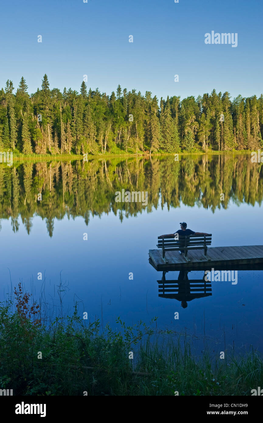 Man relaxing on a dock, Two Mile Lake, Duck Mountain Provincial Park, Manitoba Stock Photo