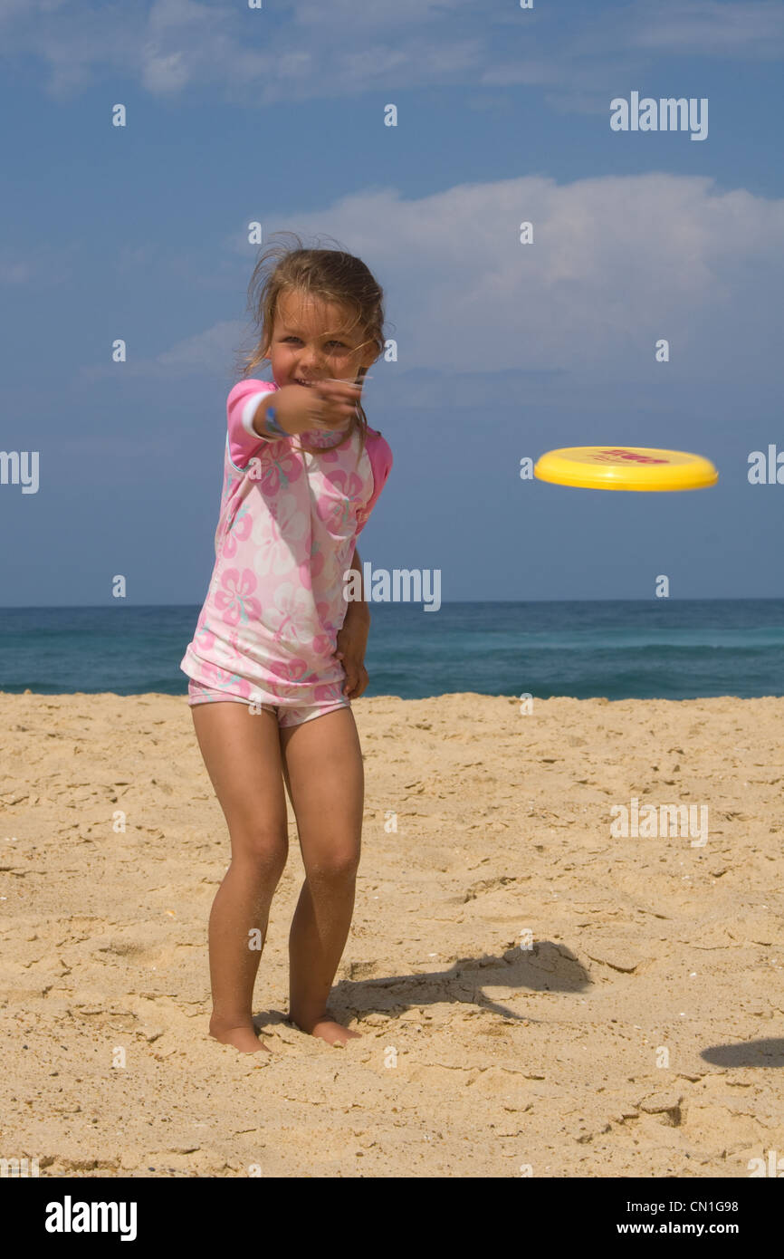 A young girl plays frisbee during her summer holiday on the beach in Europe Stock Photo