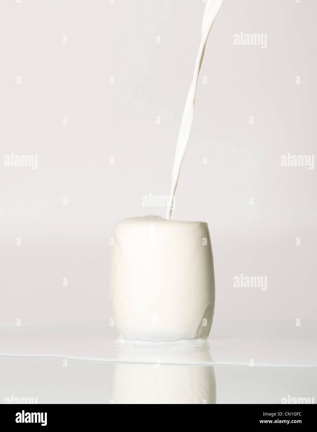Milk Pouring Into an Overflowing Glass Stock Photo
