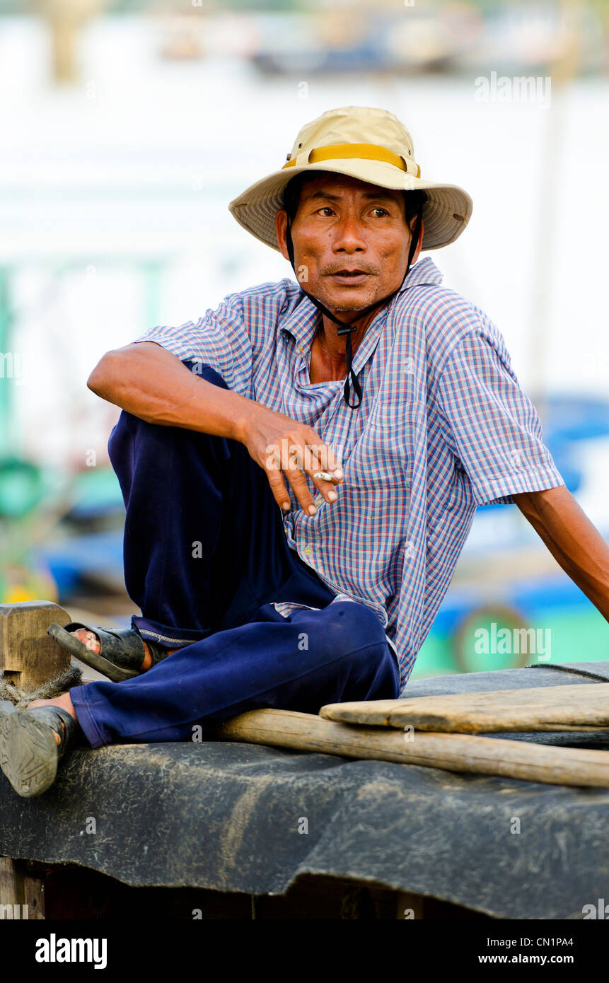 Man Smoking Cigarette on the Roof of his Boat, Hoi An, Vietnam Stock Photo