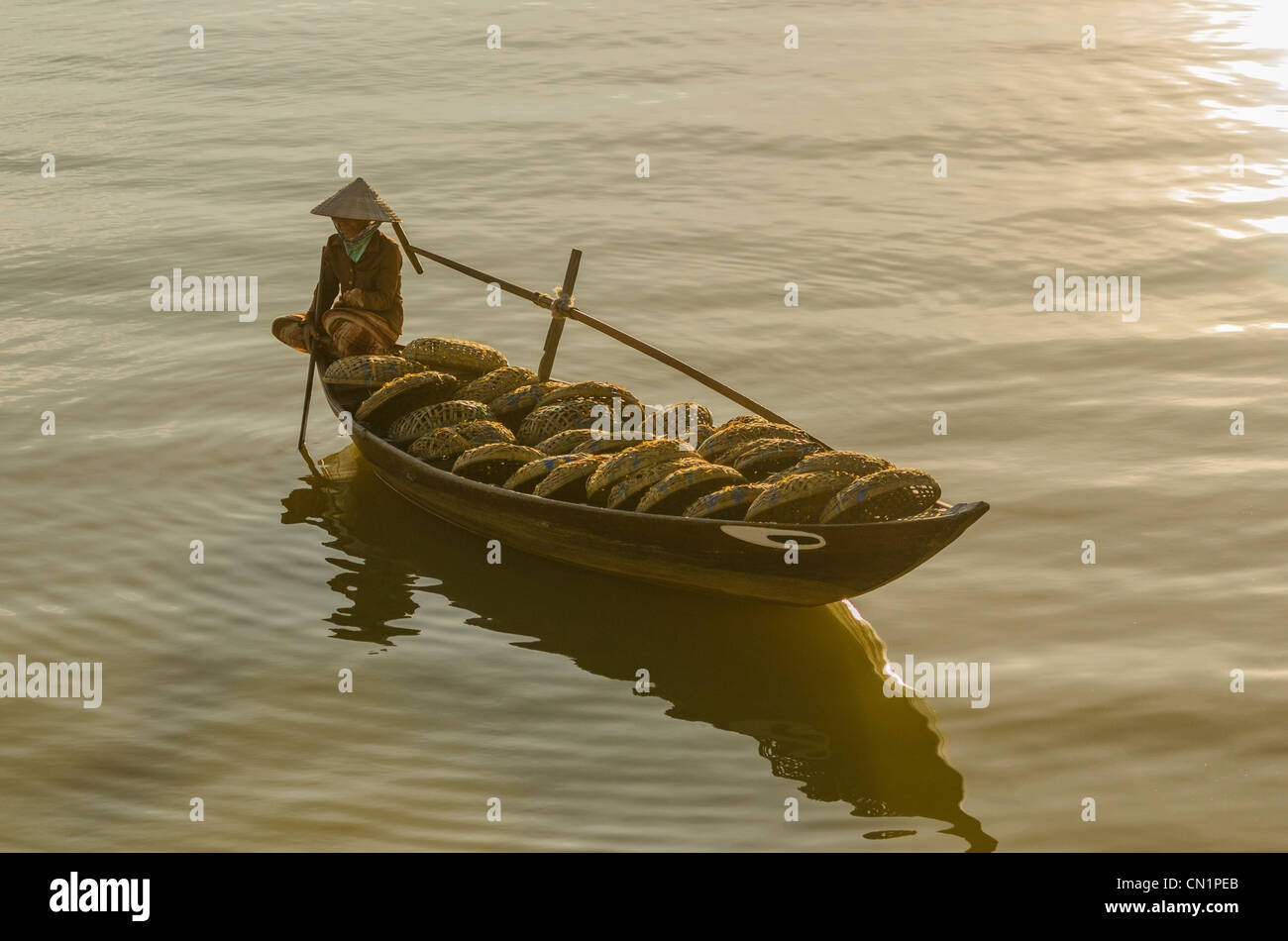 Vietnamese Woman in Conical Hat Rows Boat Filled with Fishing Baskets Stock Photo