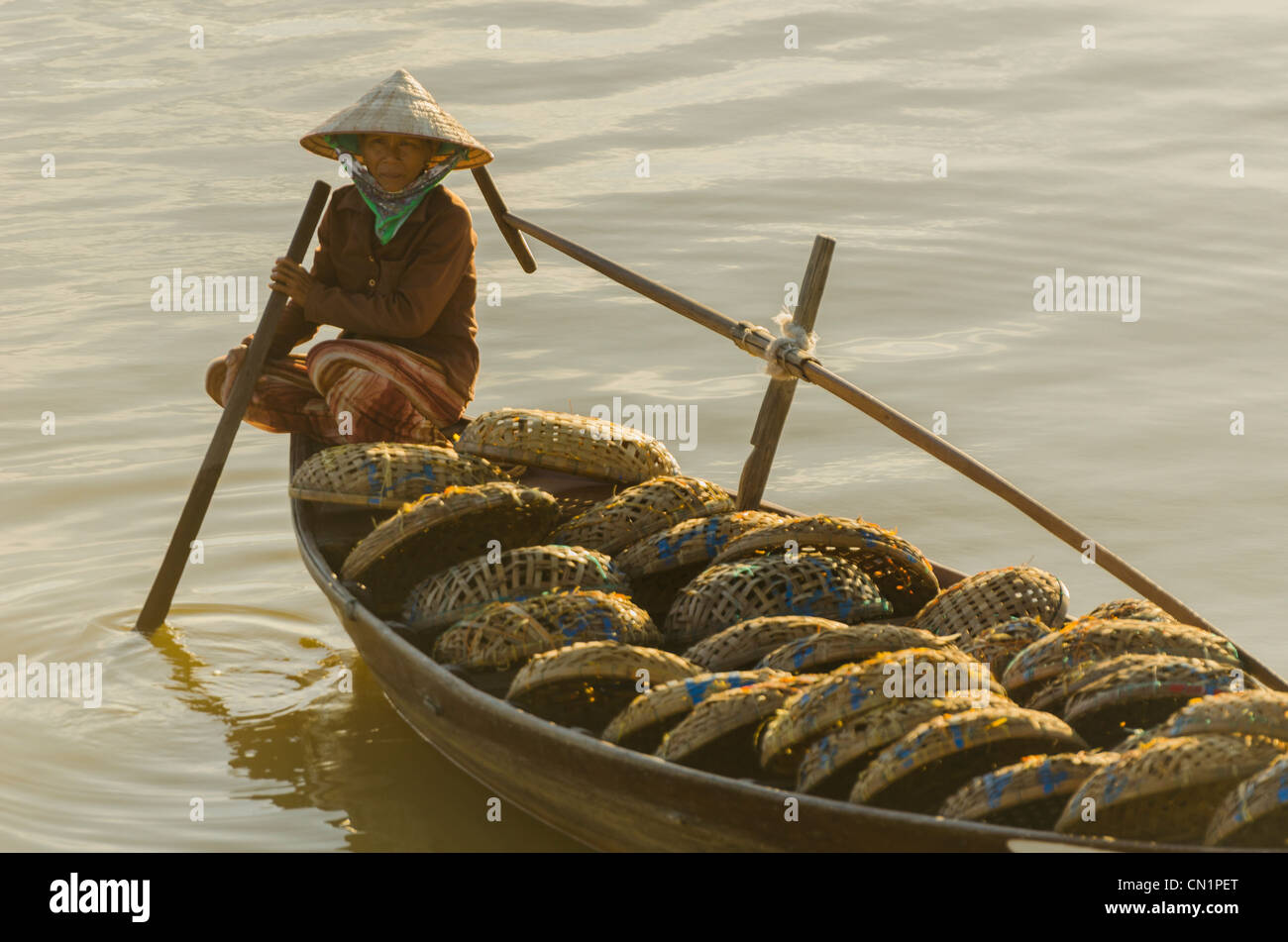 Vietnamese Woman in Conical Hat Rows Boat Filled with Fishing Baskets Stock Photo