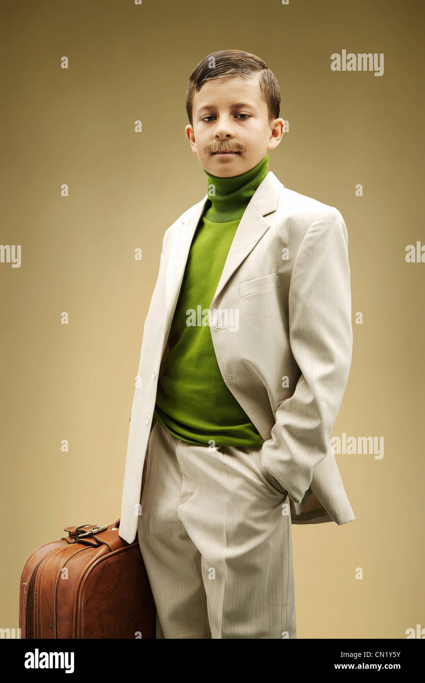 Young boy dressed in beige suit with fake mustache Stock Photo