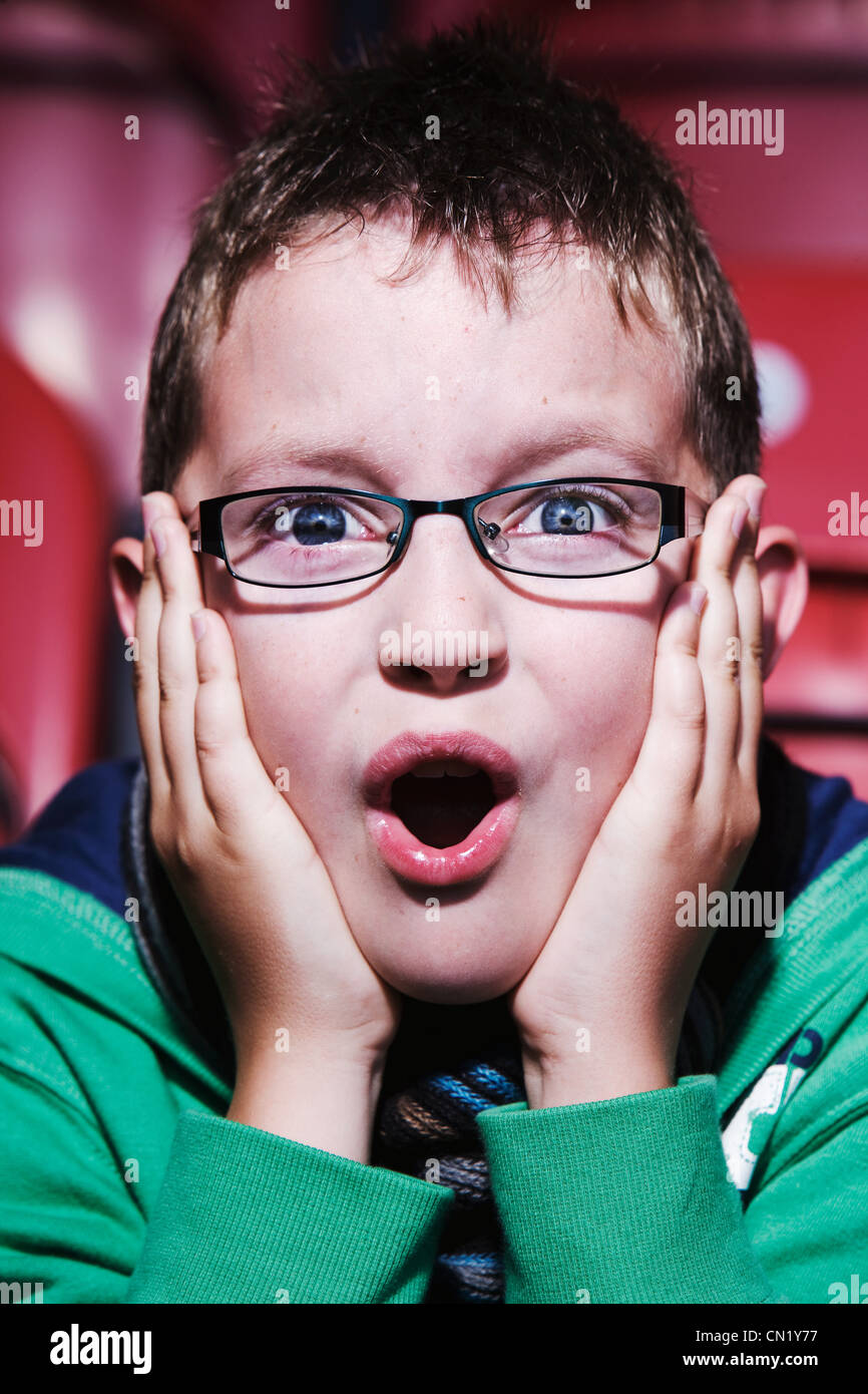 Young boy at the cinema, hands touching face Stock Photo