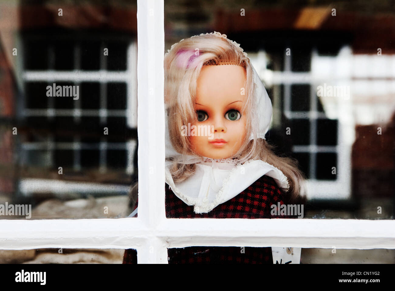 Doll looking out of window Stock Photo