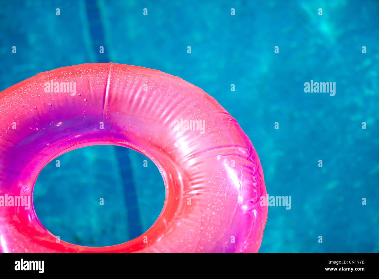 Floating inflatable toys on pool in summer lit by warm sun Stock Photo