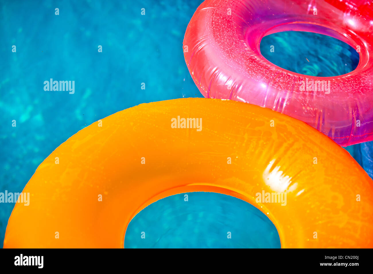 Floating inflatable toys on pool in summer lit by warm sun Stock Photo