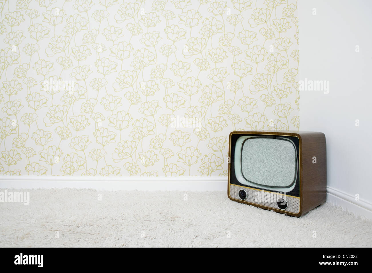 Retro television in corner of room with patterned wallpaper Stock Photo