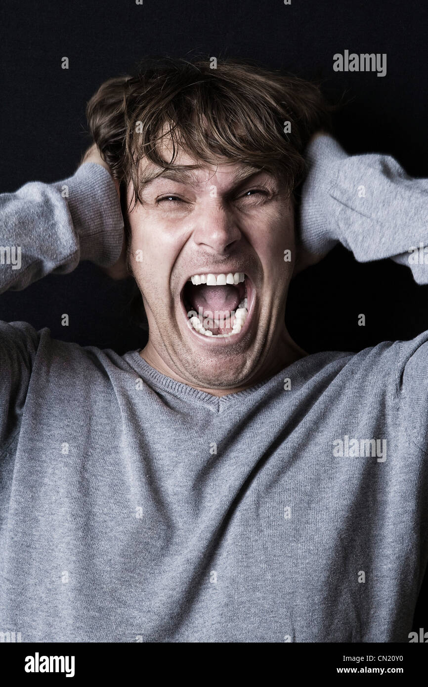 Man screaming with hands covering ears Stock Photo
