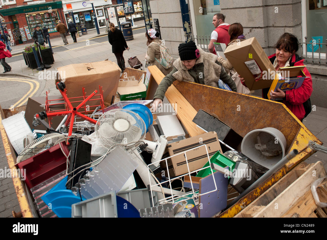 Skip raiding: People scavenging in a skip in the street for items thrown out by a shop, UK Stock Photo