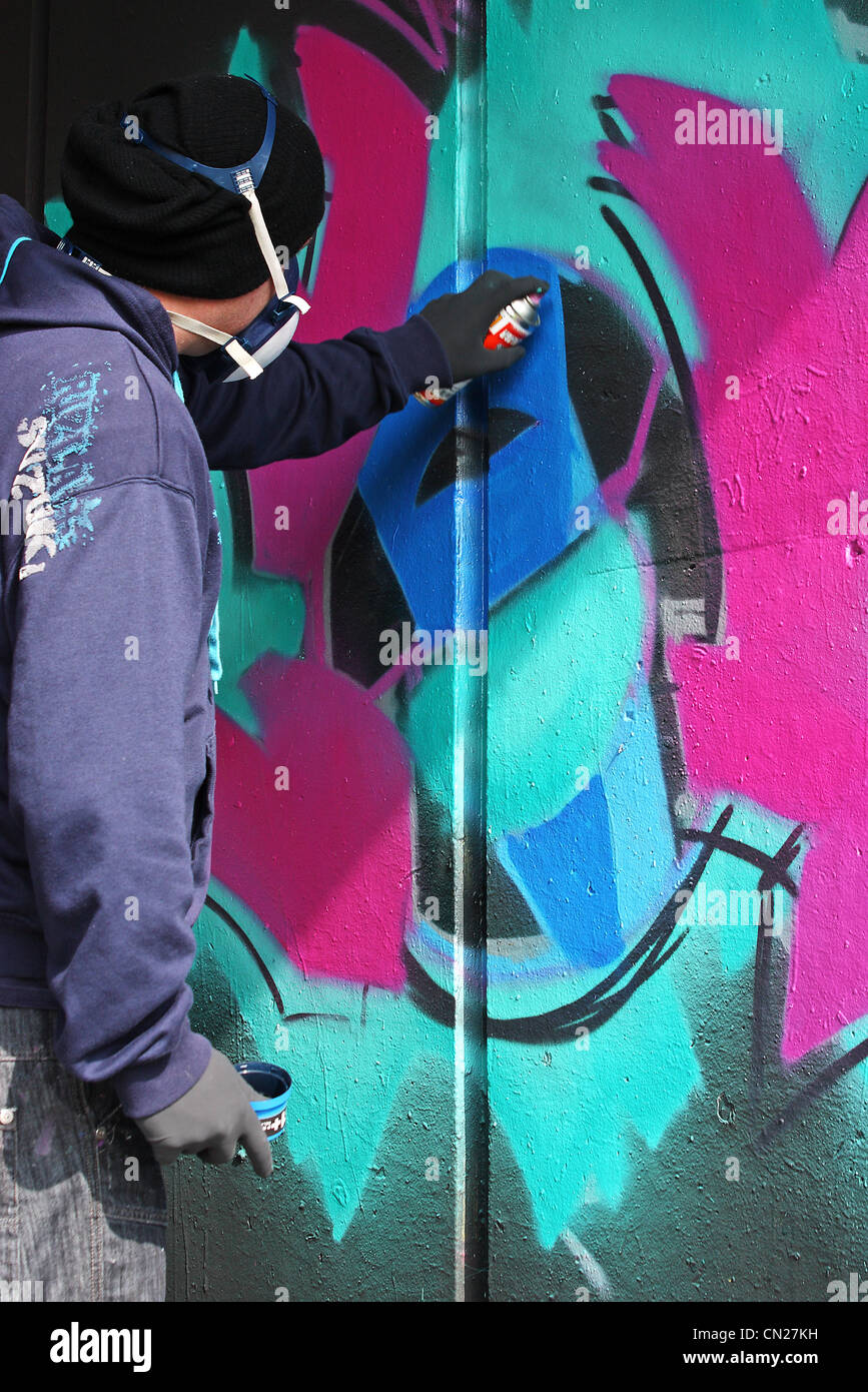 Graffiti artist spraying on a wall using an aerosol can of spray paint