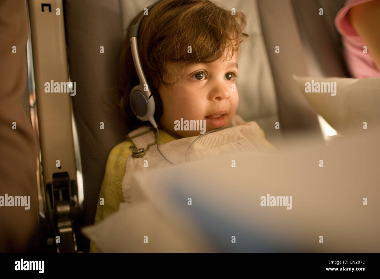 Young girl sitting on airplane wearing headphones Stock Photo Alamy