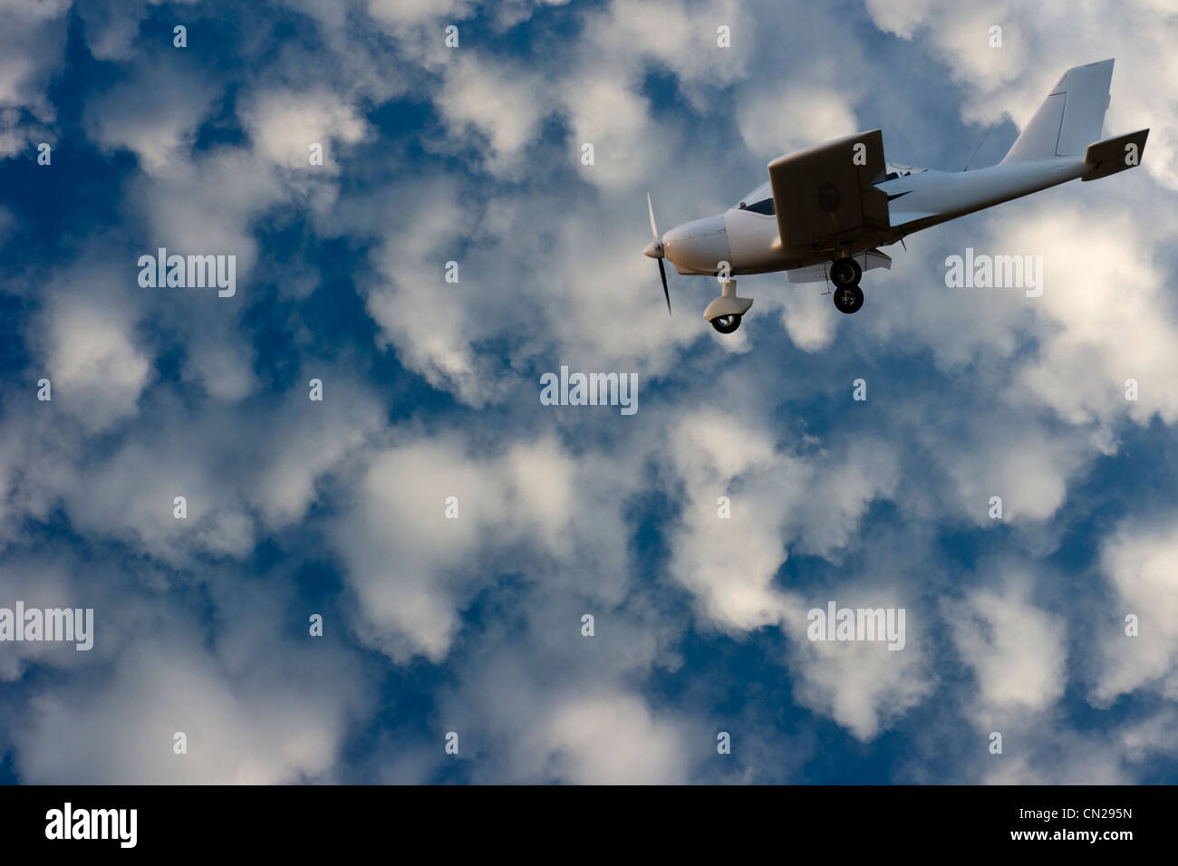 Clear blue sky with white clouds and white small airplane. Stock Photo